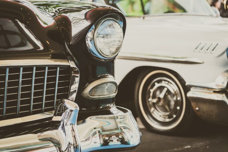 Détail avant d'une voiture de collection noire restaurée, avec phare rond et calandre chromée, lors d'un rassemblement à Lyon